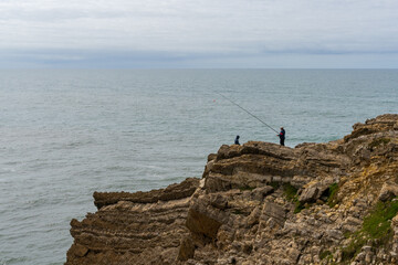 Fototapeta na wymiar fisherman fishing from a rocky cliff on the wild Atlantic coast of northern Portugal