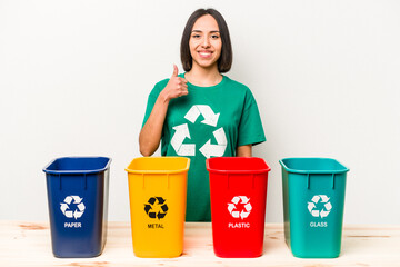 Young hispanic woman recycling isolated on white background smiling and raising thumb up