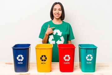 Young hispanic woman recycling isolated on white background person pointing by hand to a shirt copy space, proud and confident