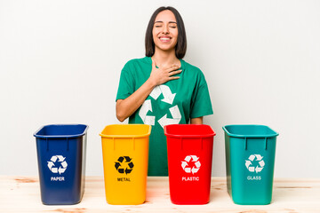 Young hispanic woman recycling isolated on white background laughs out loudly keeping hand on chest.