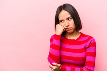 Young hispanic woman isolated on pink background who feels sad and pensive, looking at copy space.