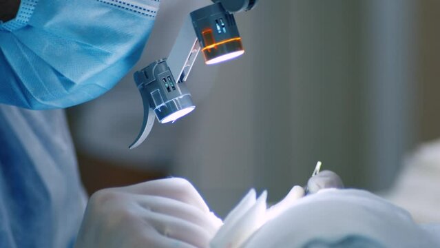 surgeon operates using microscope glasses with lenses and lamps. Microsurgery