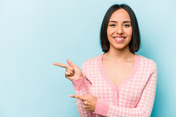 Young hispanic woman isolated on blue background excited pointing with forefingers away.