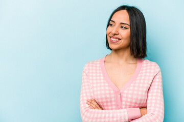 Young hispanic woman isolated on blue background smiling confident with crossed arms.