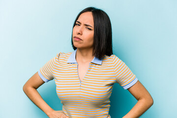 Obraz premium Young hispanic woman isolated on blue background frowning face in displeasure, keeps arms folded.
