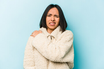 Young hispanic woman isolated on blue background having a shoulder pain.