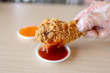 Closeup Hand Hold Chicken Fried with chilli sauce and ketchup sauce on Table 
