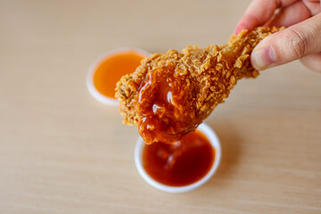 Closeup Hand Hold Chicken Fried with chilli sauce and ketchup sauce on Table 