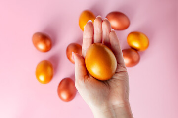 Woman holds a shiny Easter golden egg in her hand.