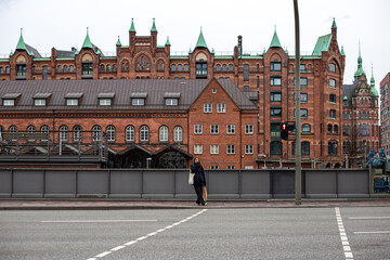 Naklejka premium A young woman stands at a crosswalk in the city.