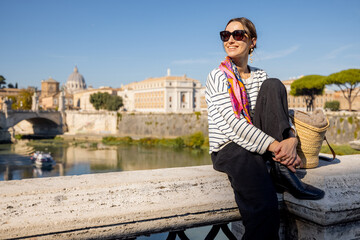 Woman enjoying beautiful view of Rome city and Vatican standing on the bridge on a sunny autumn...