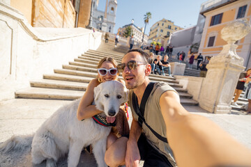 Man and woman taking selfie photo with a dog on backgorund of Spanish steps. Concept of happy...