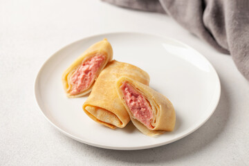 Stuffed pancakes or crepes in a plate and jam on the table. Tasty breakfast