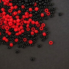 Glass beads. Black and red colors. Isolated on black background, top view.