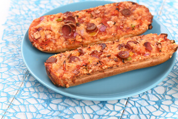 Baked baguette with cheese and sausage on a wooden tray.