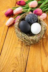 black colors painted easter eggs in decor nest. Happy Easter holiday card
