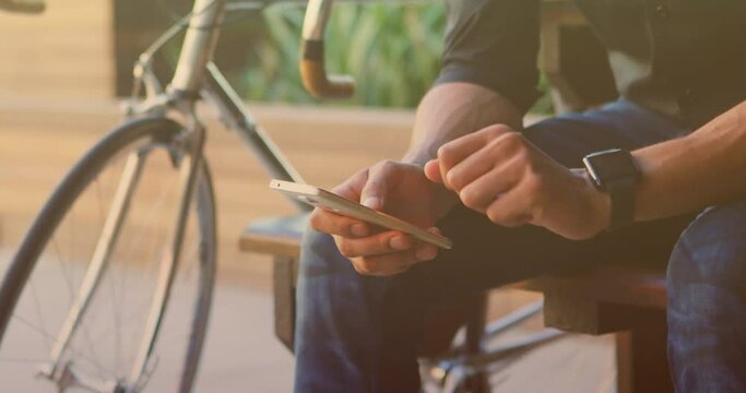 Animation of biracial man sitting and using smartphone with bicycle