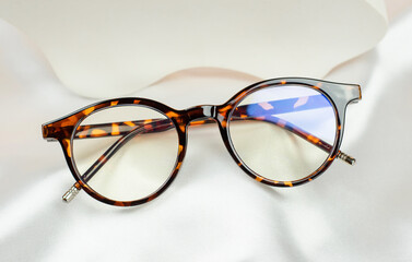 Leopard glasses on white silk fabric, close-up