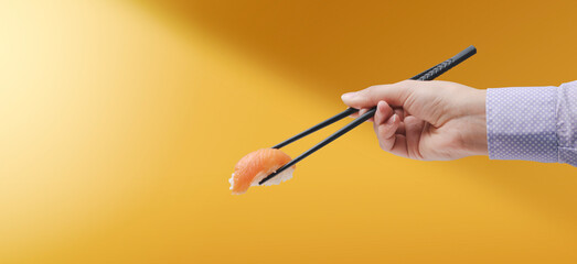 Woman eating sushi using chopsticks
