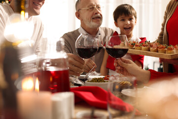 Family clinking glasses of wine at festive dinner, focus on hands. Christmas celebration