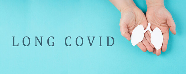 The words long covid are standing on a paper, hands hold a lung, breathing problems after Covid-19...
