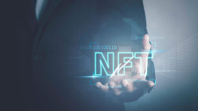 NFT non fungible tokens concept. Businessman holding digital unique art NFT text hologram on blue light
