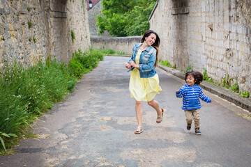 Mother and little eastern handsome baby boy playing outdoor in old town. Happy Mixed race family in Europe concept