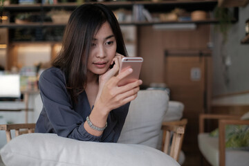Happy asian woman using mobile phone or smartphone in coffee shop with vintage tone cafe , hand hold smartphone payment app shopping online, ordering delivery
