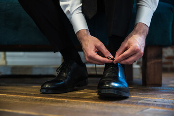 groom putting on wedding shoes 