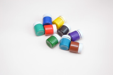 Closed jars with gouache of different colors on a light background. Creativity, hobby.