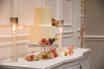 wedding cake on table with flowers and candles 