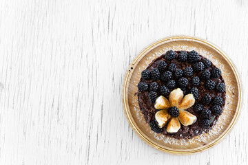 Raw rich dark chocolate cake on white table. Minimalism food photography concept
