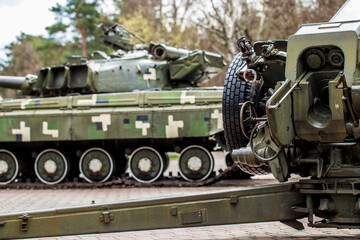 Tank and howitzer stand on the street in Ukraine. In the Kiev park there is a gun and a green tank.