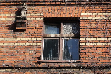 Window of brick old building and small statue, Upper Silesia. Piekary Slaskie, Poland.