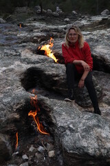 girl sitting near Flames from the underground of Mount Chimera, Cirali, yanartas Milli park, Turkey	
