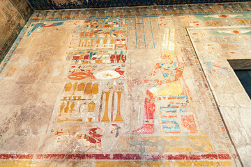 Obraz premium Hieroglyphs and paintings carved in sandstone columns in Hatshepsut temple in Luxor. Egyptian heritage and civilization concept
