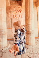 Follow me, happy woman traveler to the ruins of the ancient egyptian Hatshepsut temple in the...