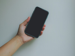 Hand holding the smartphone with blank black screen on the white background.