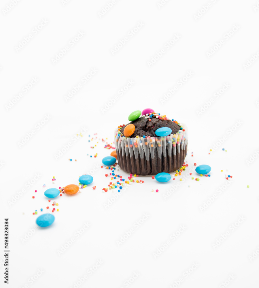 Wall mural chocolate muffin in brown paper with chocolate pieces isolated on white background