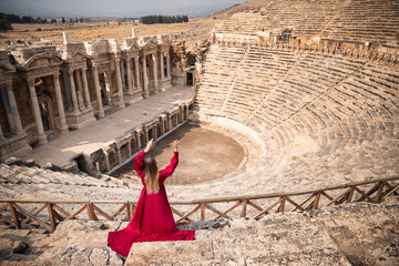 Hierapolis ancient city Pamukkale Turkey, woman in red dress background ruins Unesco sunset