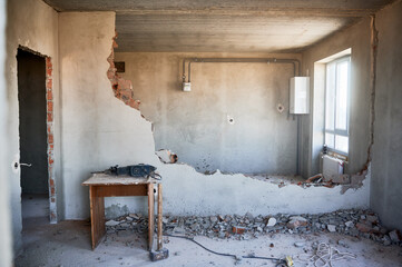 Housing redevelopment. Small table with perforator, sledgehammer placed on floor at partially...