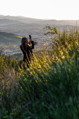 young blonde girl with smartphone enjoys the beautiful landscape in front of her