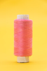single pink color yarn or spool thread over on yellow background
