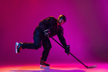 One man, professional hockey player training isolated over pink background in neon light
