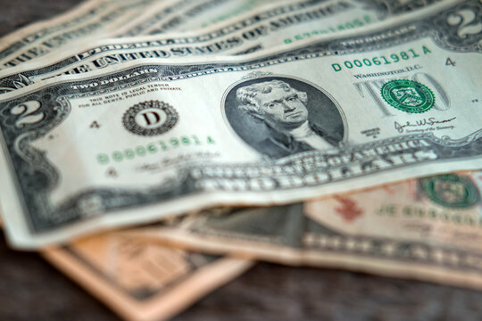 Two dollar bill on old wooden table. Money, US dollar bills background. Money scattered on the desk. Photography for Finance and Economy concepts.