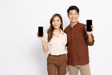 Portrait of young smiling Asian couple holding and showing mobile phone application isolated on...