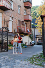 Obraz premium Cheerful travelers holding binoculars and map near building on urban street.