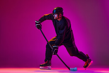 One man, professional hockey player training isolated over pink background in neon light. Championship