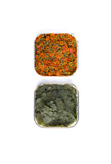 Dry green and red compound fish feed flakes in a transparent boxs on White background. Top view.