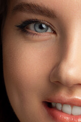 Fototapeta premium Half beauty portriet woman smiling at the camera with a snow-white smooth. Beautiful natural makeup, puffy lips, smooth and thick eyebrows, extremely long eyelashes. Clean fresh skin